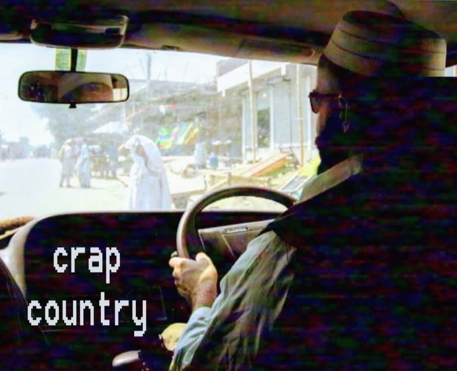 In-car view of street with "crap country" overlay